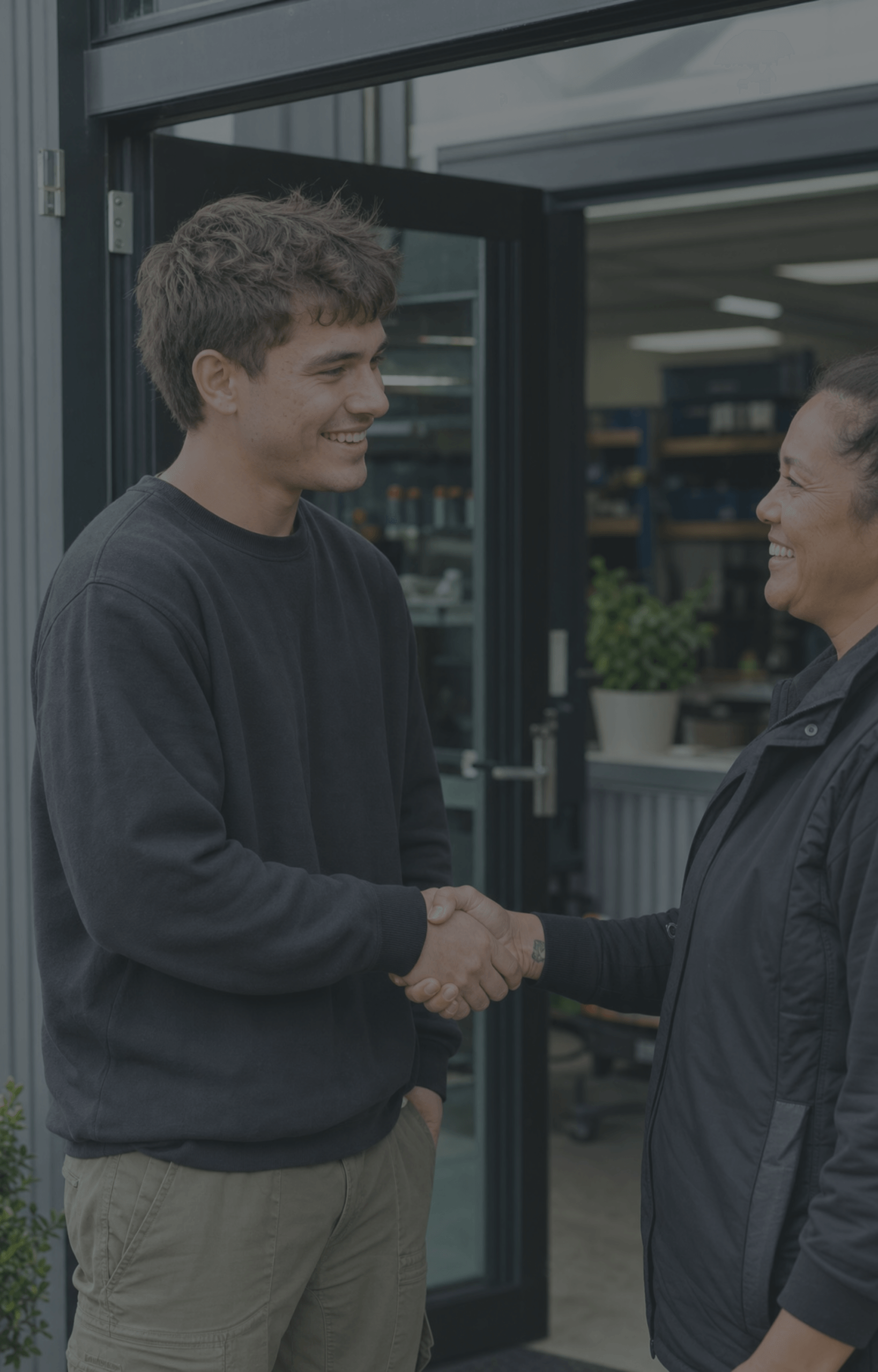 pakeha-young-man-pacific-maori-woman-employment-handshake-workplace-dark-overlay-nz